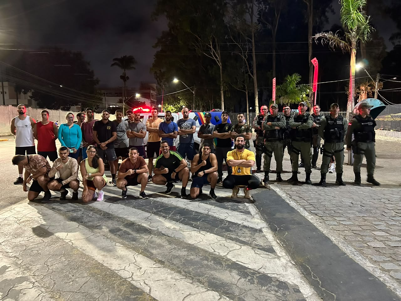 Turma de alunos do Rumo ao TAF reunida com policiais militares após treino noturno